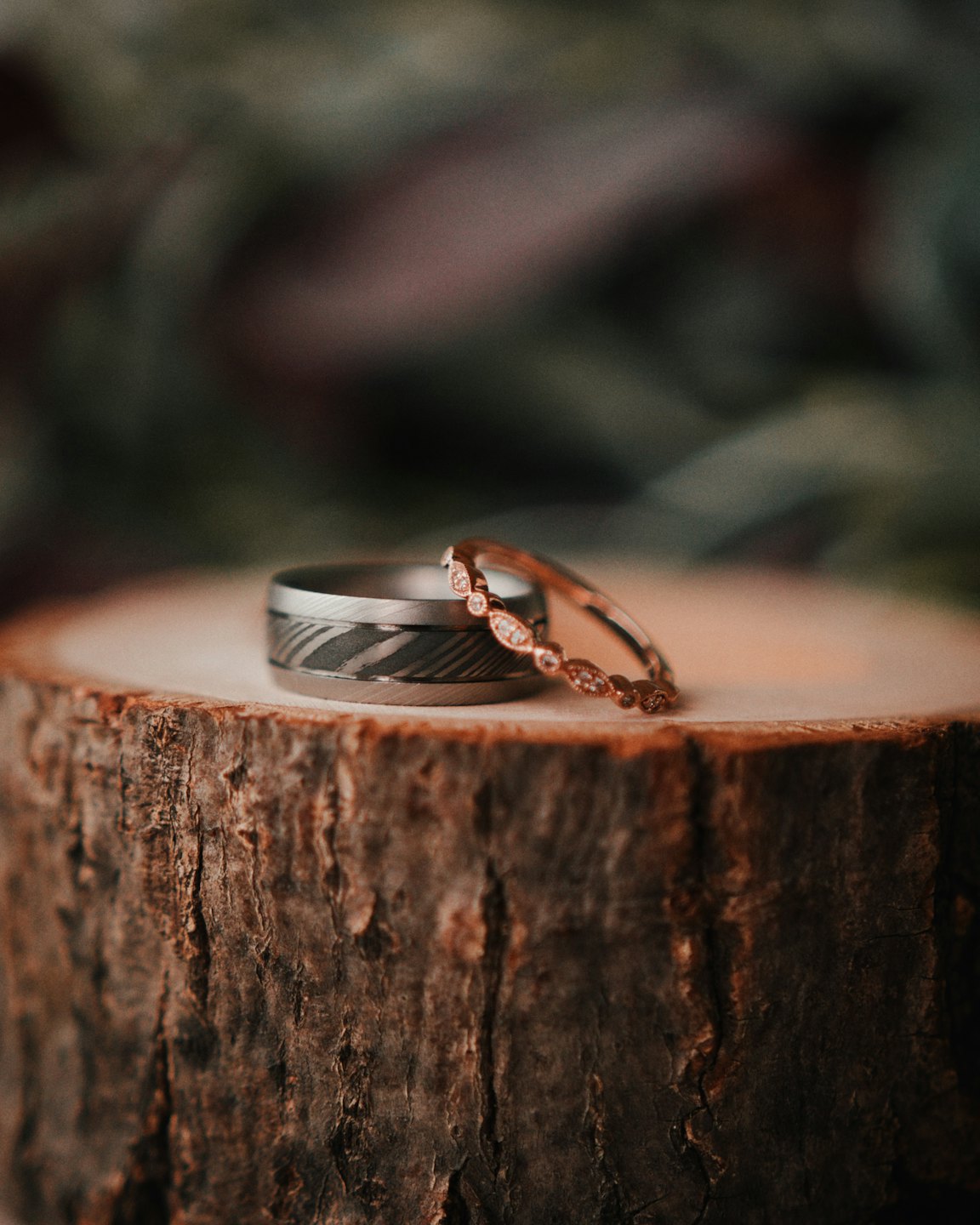 Rose gold and textured gray wedding rings resting on wood.