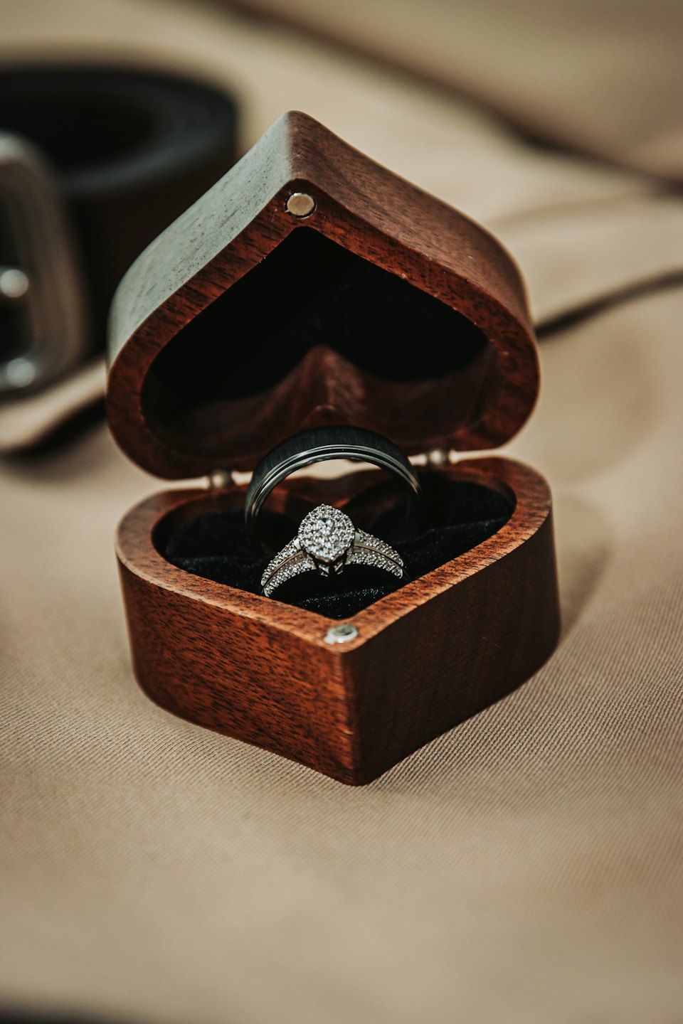 Two wedding rings rest inside an open heart-shaped wooden box.